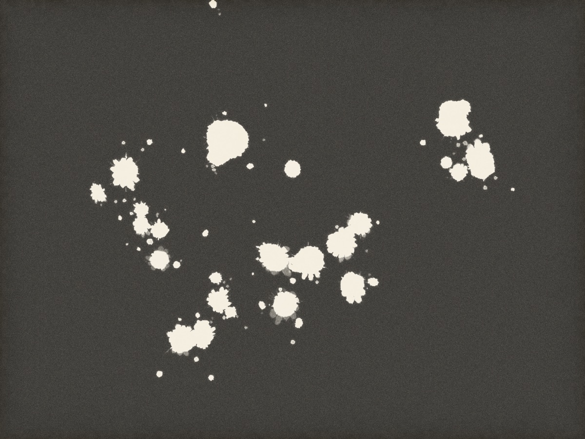 Bleach spattered onto a dark print: splats with crowns and satellite drops